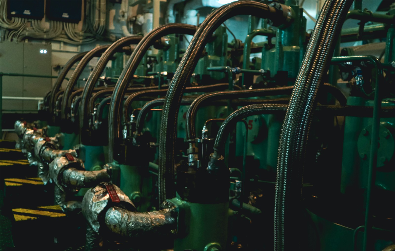Photo by iSawRed on Unsplash Engine room aboard a vessel, rows of engine blocks connected by flexible hoses