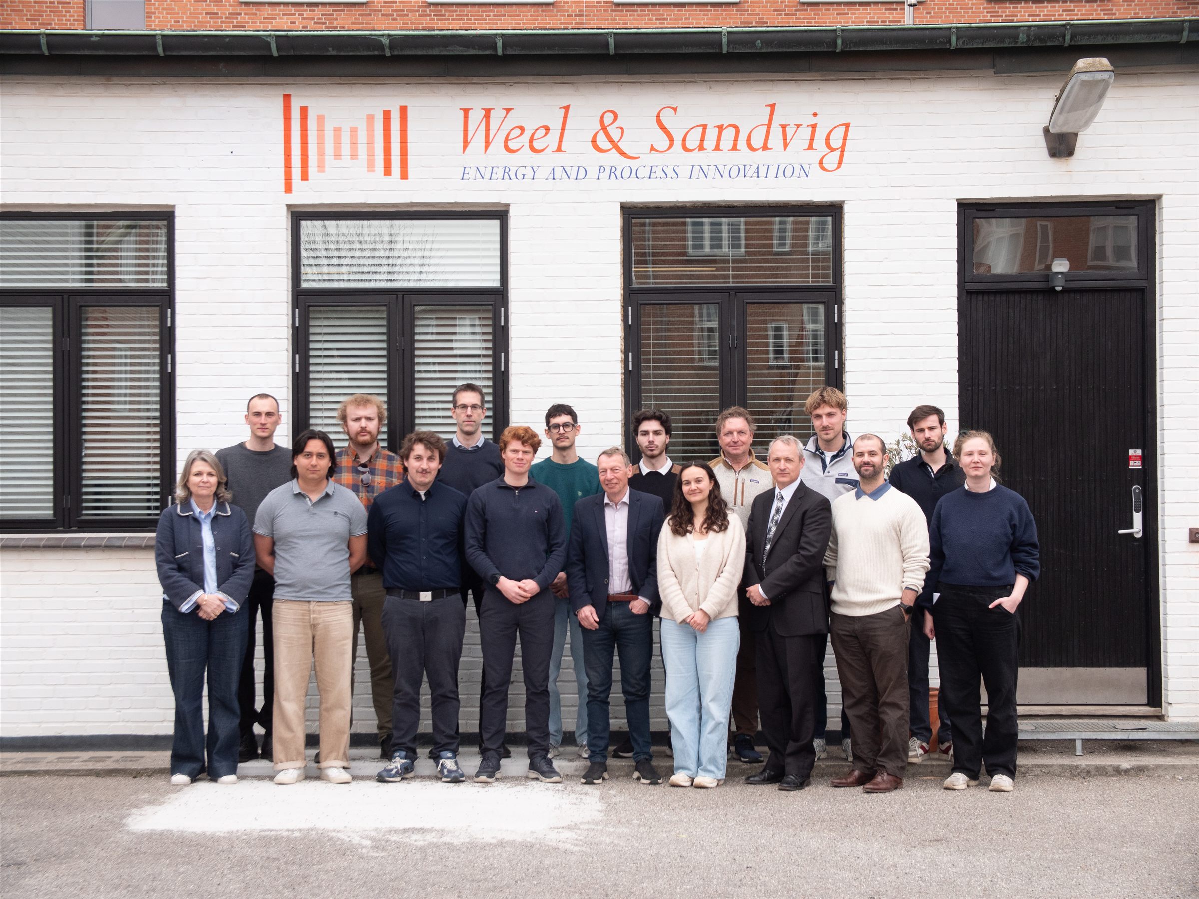 The Weel & Sandvig team posing together outside the office